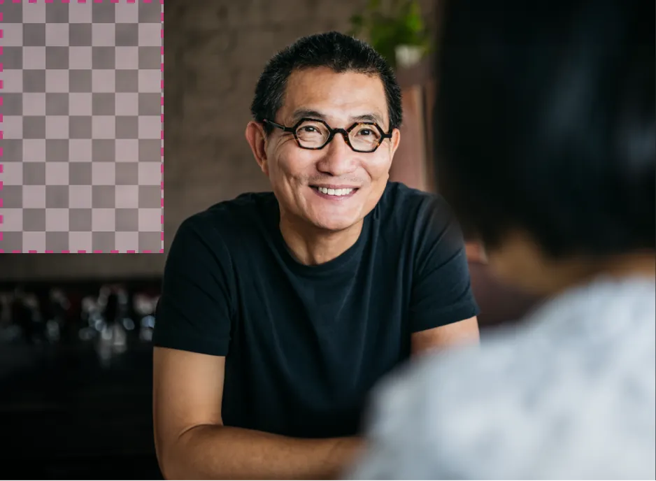 A man wearing glasses smiles as he converses. A dashed line in the top left corner indicates where we would like to add a new object.