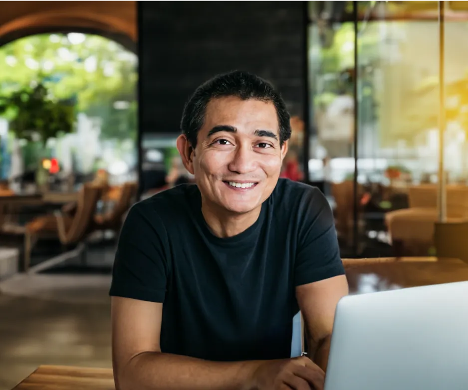 The man wearing glasses smiling as he converses, with an empty cafe in the background