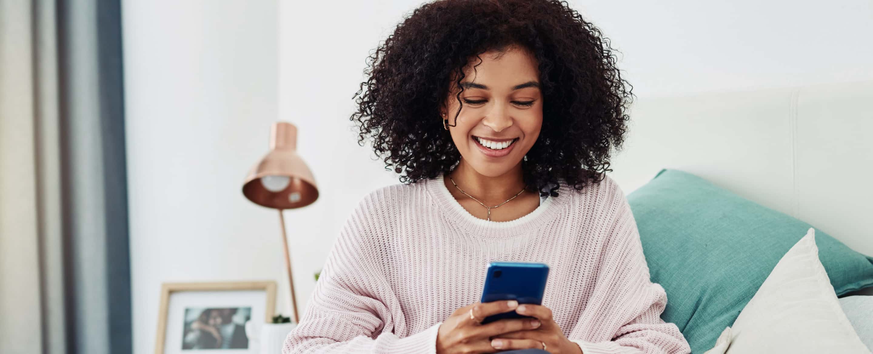Photograph of person in living room, smiling at their phone
